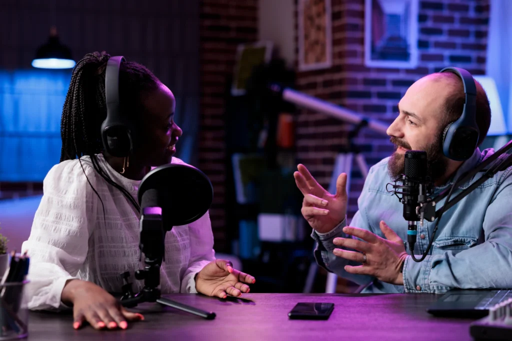 Two podcasters trade animated ideas in a moody brick-walled studio.