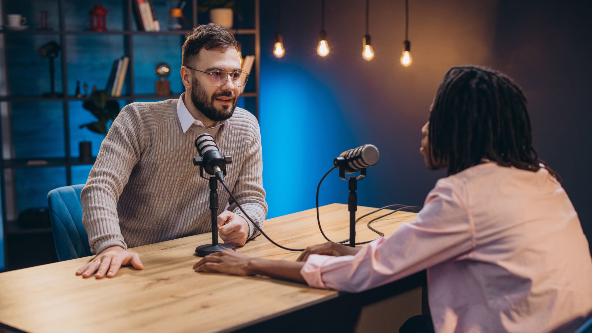 Image for How to Publish a Podcast, showing two people sitting at a table with microphones, actively engaged in a podcast recording session.