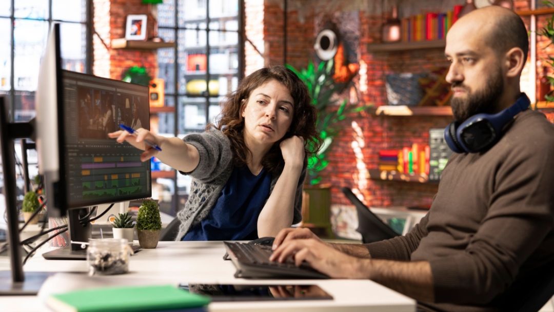 Audio producer and engineer discussing podcast production costs at professional studio workstation, illustrating real costs and financial impact of outsourcing podcast work